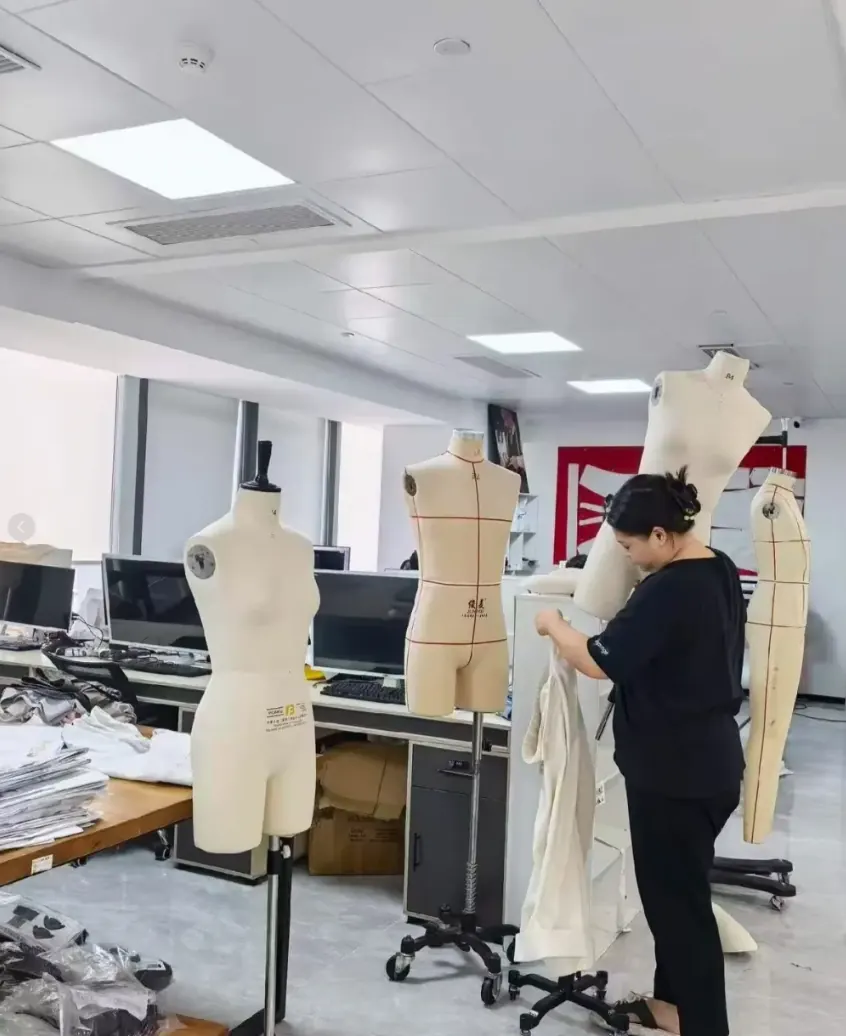 Fashion designer working with garments and dress forms in a studio