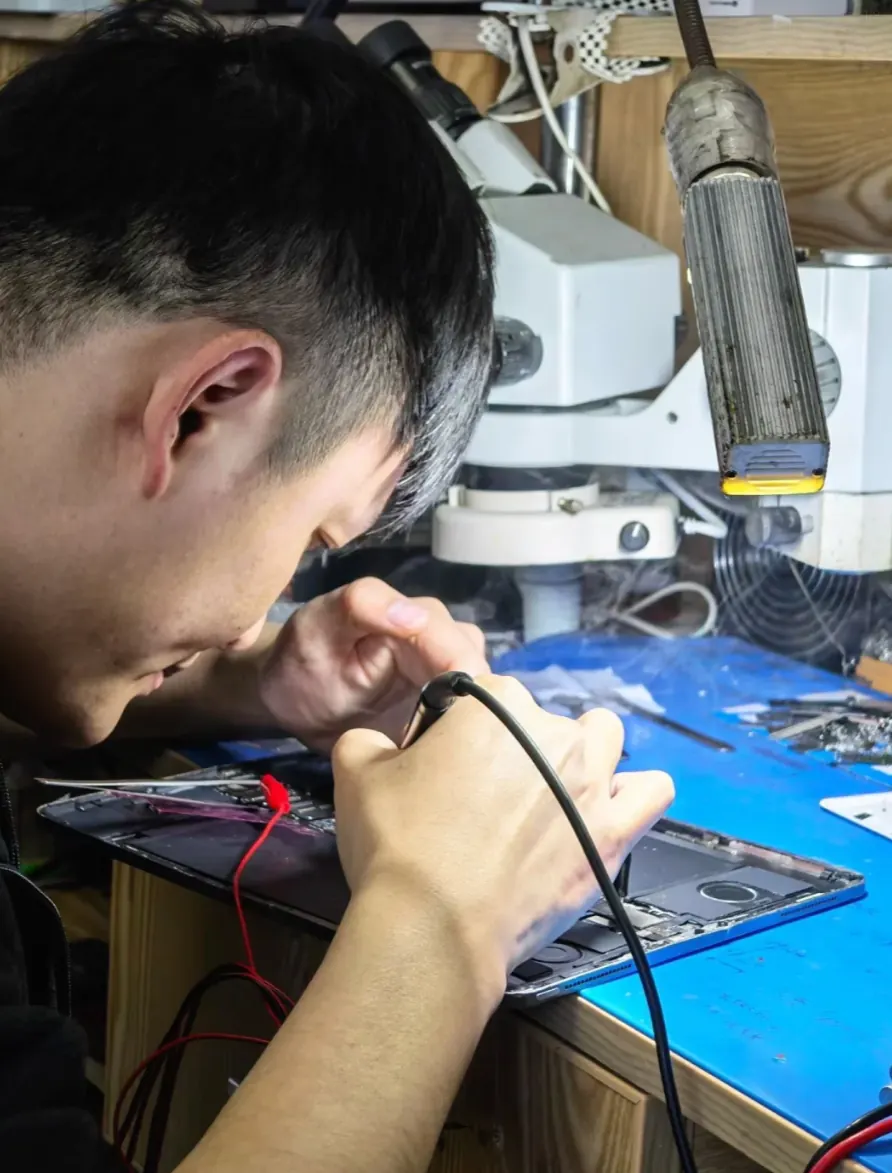 Technician repairing a mobile device at a specialist workbench